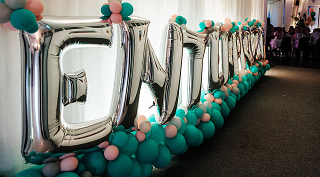 Silvriga ballonger som bildar texten Enterprize hänger på en vägg.